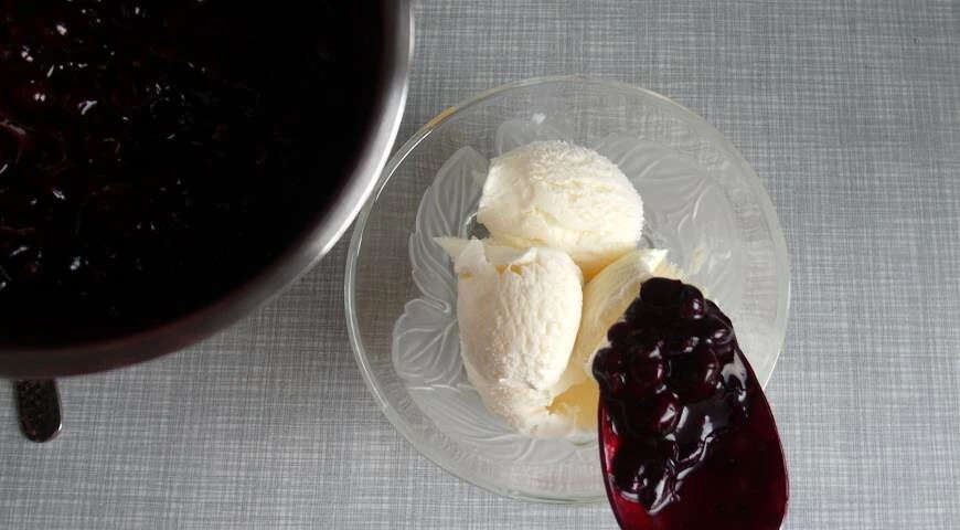 Cold dessert of ready-made ice cream with walnuts and blackcurrant sauce