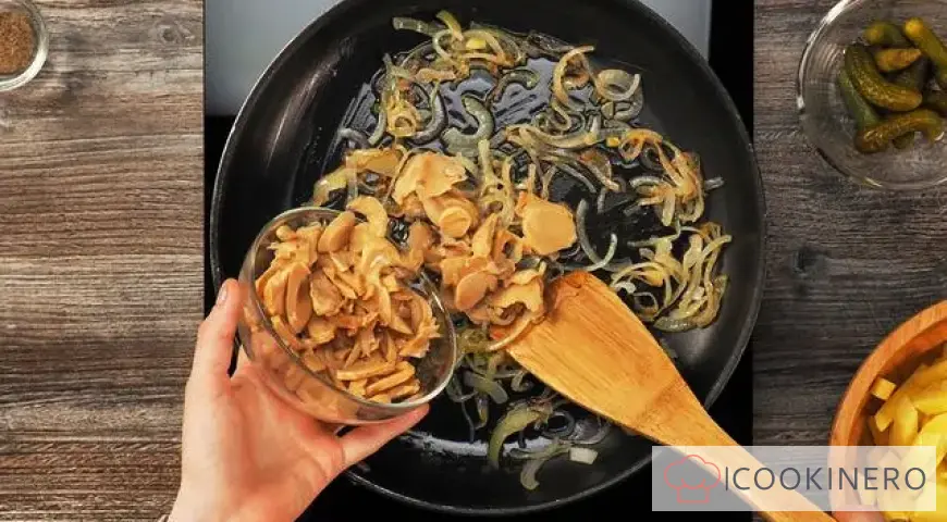 Fried potatoes with canned mushrooms in a frying pan