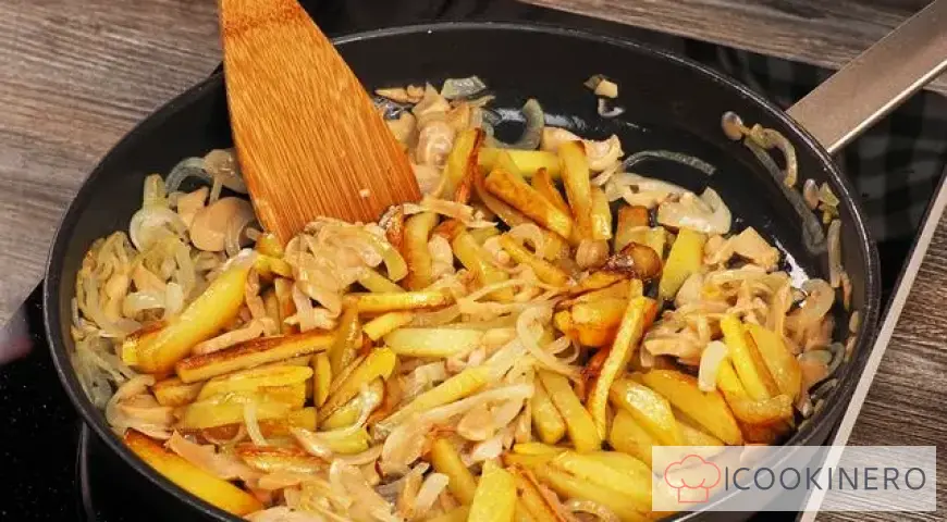 Fried potatoes with canned mushrooms in a frying pan
