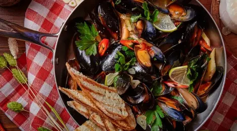 Una padella di cozze in salsa di pomodoro piccante con capperi