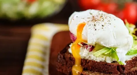 Sándwich de pan integral con requesón, ensalada mixta y huevo escalfado