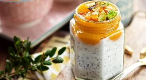 Frühstück in einem Glas Chiapudding, Mangopüree, kandierten Orangen und Pistazien