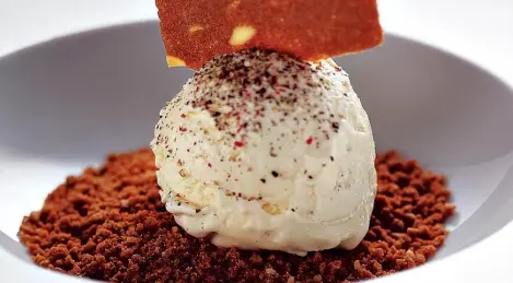 Helado cremoso de pimienta sobre migas de galleta de almendras